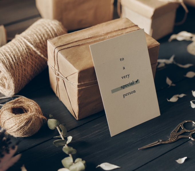 close-up-of-card-for-special-person-leaning-on-packaged-gift-scissors-twines-petals-on-wooden-table
